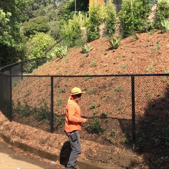 A man walking down a dirt road next to a fence