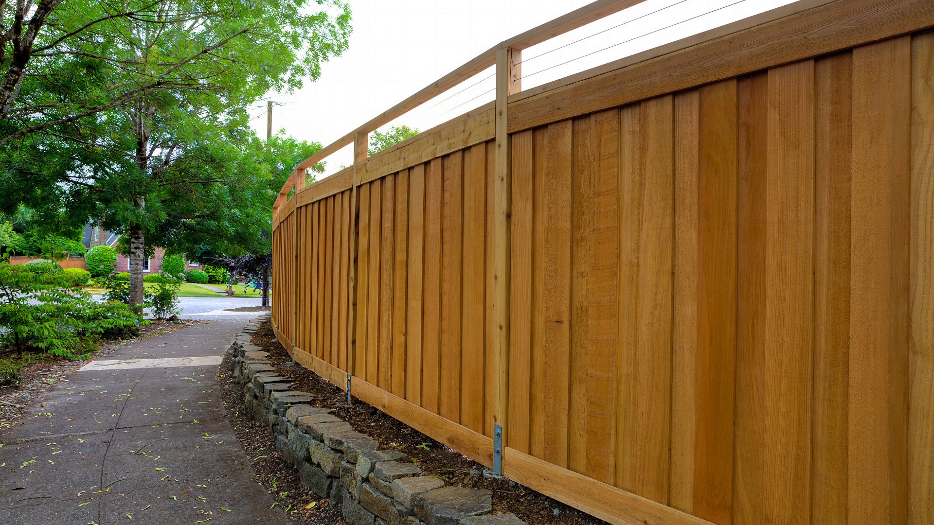 A wooden fence next to a sidewalk in a park