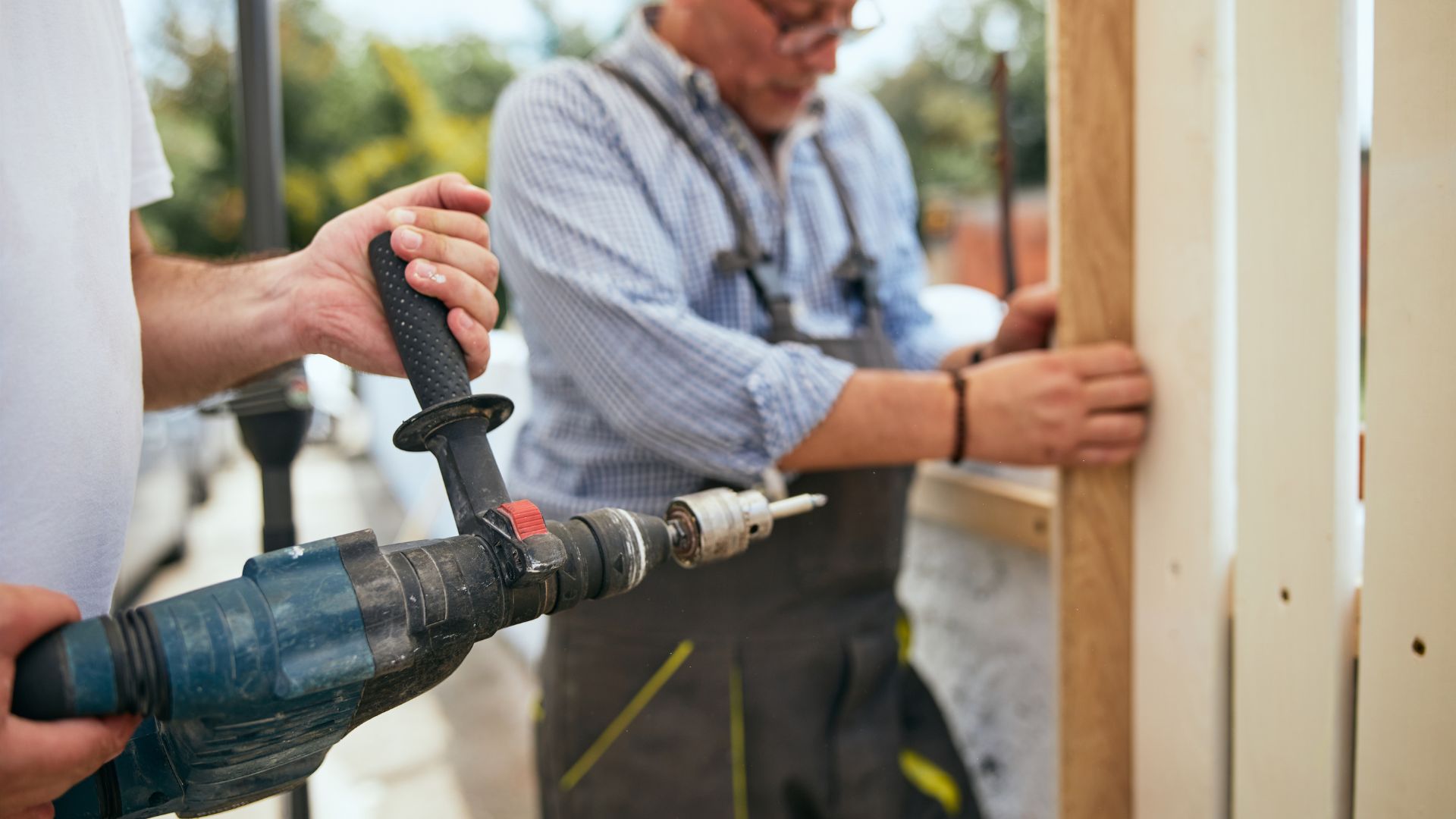 A couple of men working on a piece of wood