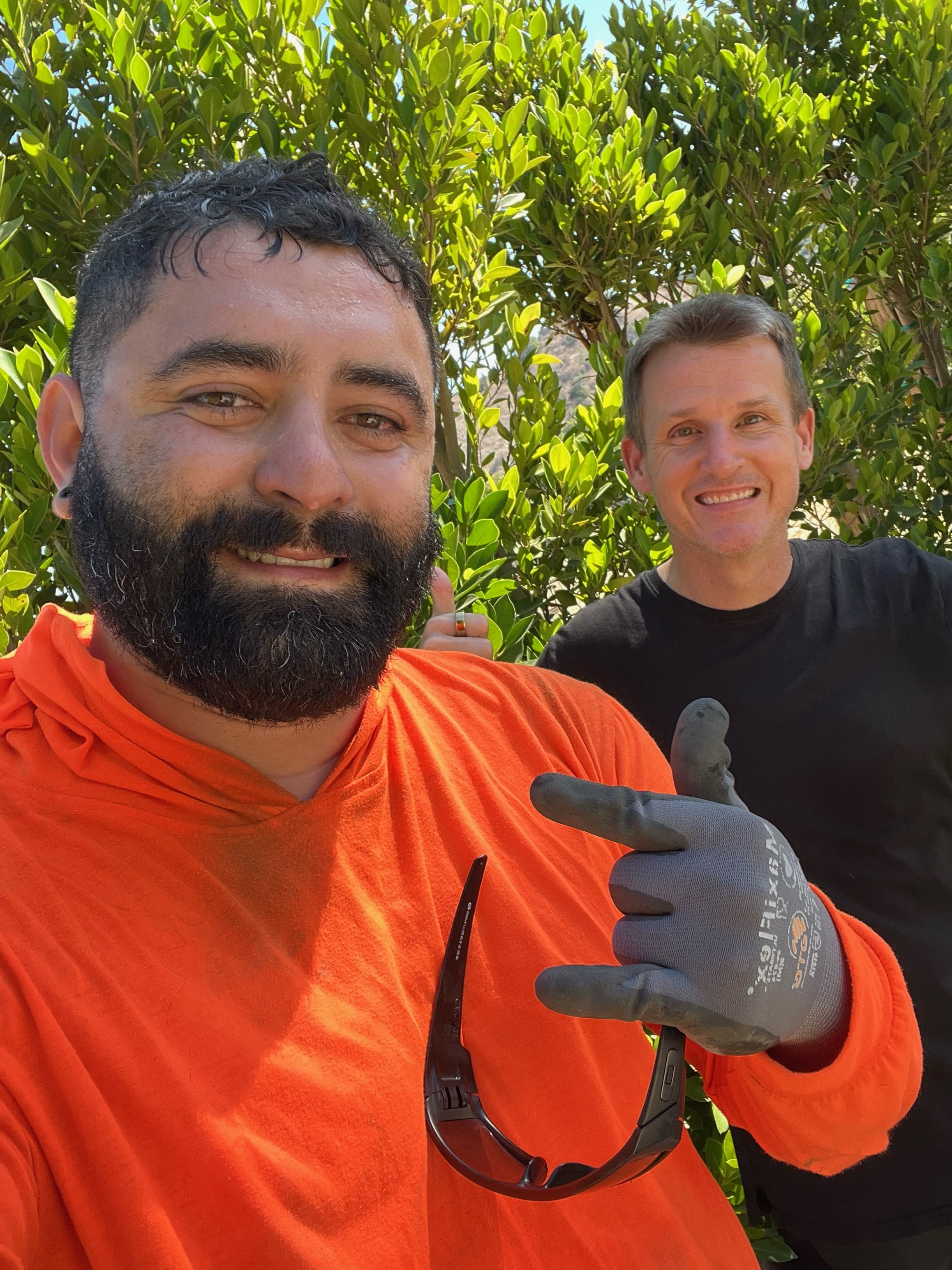 Two men standing next to each other in front of trees